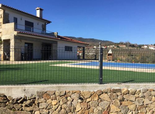 a fence in front of a house with a swimming pool at Quinta do Couto (alojamento local) in Celorico de Basto
