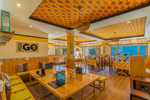 a restaurant with wooden tables and yellow chairs at The Hosteller Manali, Old Manali in Manāli