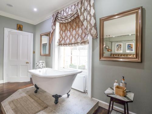 a bathroom with a white tub and a mirror at 3 Old Market Place in Harleston