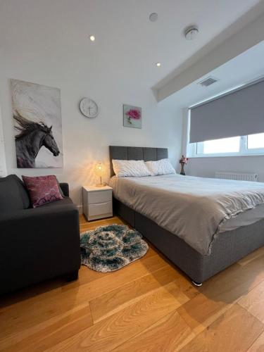 a bedroom with a bed and a couch and a horse painting at Modern 1 bedroom apartment in the center of Croydon in Croydon
