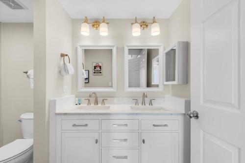 a white bathroom with two sinks and a toilet at Island Princess 710 in Fort Walton Beach