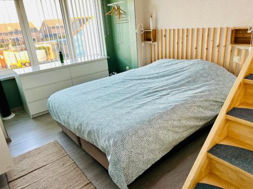 a bedroom with a bed with a blue blanket at La Cabane de la mer in Bredene