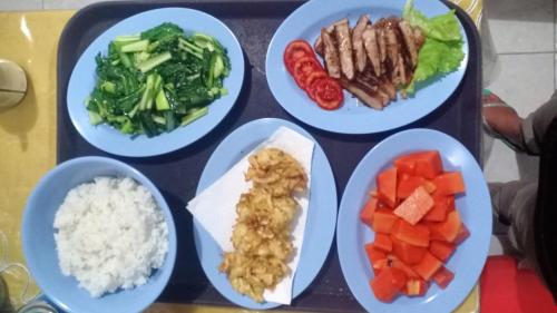 a tray with four plates of food on a table at Tangkoko Gallery Guest House and Resto in Rinondoran