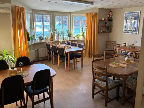 ein Esszimmer mit Tischen, Stühlen und Fenstern in der Unterkunft Hälsokällans Bed and Breakfast in Kyrkhult