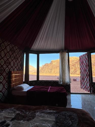 a bedroom with a bed and a view of the desert at Wadi rum Golden land camp in Wadi Rum