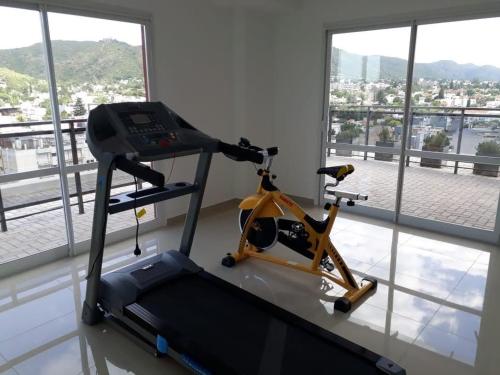 a gym with a treadmill in a room with windows at Edificio Leonardo Apart Centro in Villa Carlos Paz