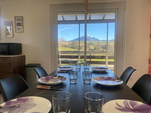 a dining room table with chairs and a large window at Appartement spacieux et lumineux - 10 personnes - entre lacs et montagnes in Fillinges