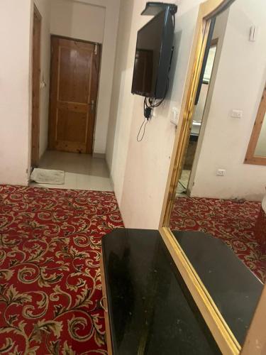Habitación con TV y alfombra roja. en Sana Challet Manali, en Manali