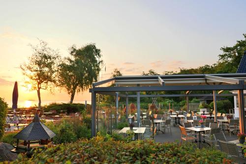 a restaurant with tables and chairs in a garden at Hotel Wilhelmshöhe in Warnemünde