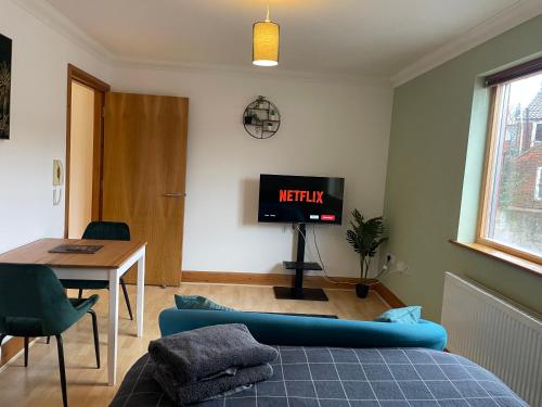 sala de estar con sofá azul y TV en Lovely Studio Apartment in the Center of Norwich en Norwich