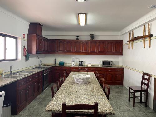 a kitchen with wooden cabinets and a table with chairs at LUZ E SAL by Stay in Alentejo in Cavaleiro