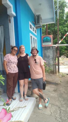 three people standing in front of a blue building at Tangkoko Gallery Guest House and Resto in Rinondoran