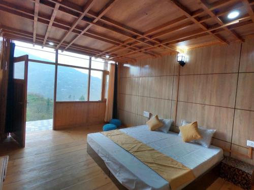 ein Schlafzimmer mit einem Bett und einem großen Fenster in der Unterkunft Hotel Mountaineers Saga in Narkanda