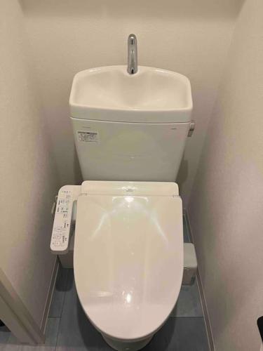 a white toilet in a bathroom with a remote control at Holy Planet in Tokyo