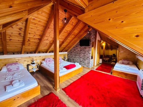 Cette chambre mansardée comprend 2 lits et un tapis rouge. dans l'établissement Kore Guest House, à Gjirokastër
