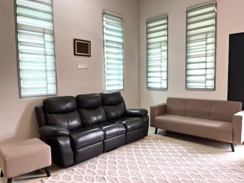 a living room with a leather couch and a chair at Homestay Ashad in Kuantan
