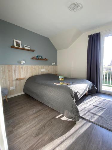 a bedroom with a bed and a large window at l'appartement la Pommeraie in Branville