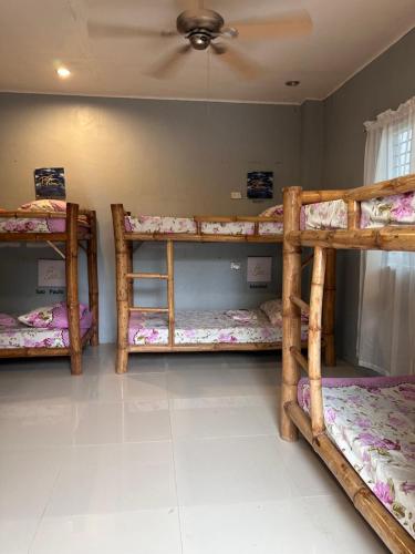 three bunk beds in a room with a ceiling at Lionfish Backpackers Hostel Malapascua in Daanbantayan