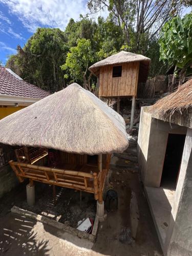 a hut with a straw roof next to a building at Lionfish Backpackers Hostel Malapascua in Daanbantayan