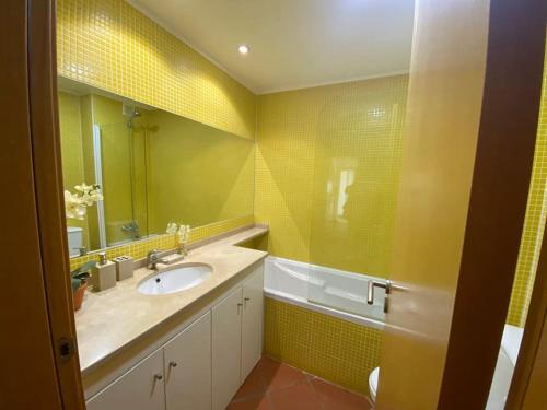 アルマカオ・デ・ペラにあるOcean Terrace Apartmentの黄色のバスルーム(シンク、鏡付)