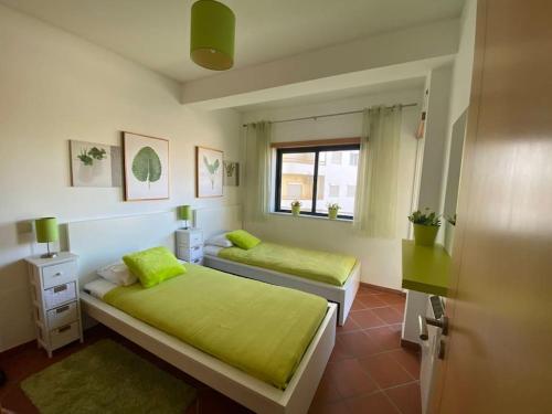 アルマカオ・デ・ペラにあるOcean Terrace Apartmentのベッドルーム1室(ベッド2台、緑のシーツ、窓付)