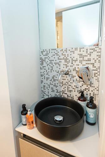 a black sink in a bathroom with a mirror at Hurban Apartments Venezian in Trieste