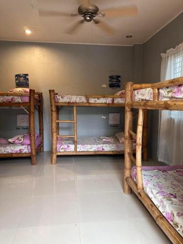 three bunk beds in a room with a ceiling at Lionfish Backpackers Hostel Malapascua in Daanbantayan
