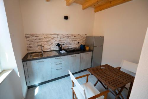 a kitchen with a sink and a table and a refrigerator at Casa Mirto in Bosa