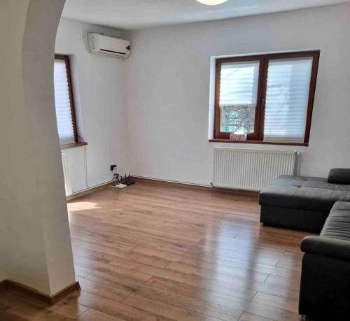 an empty living room with a couch and two windows at Charming two- bedroom house in Bucharest