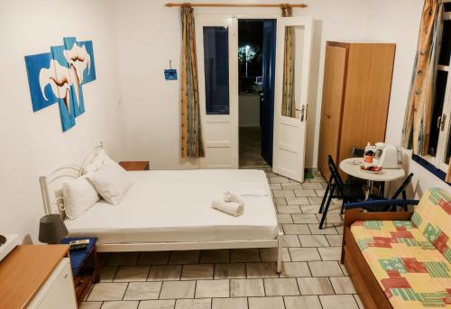 1 dormitorio con cama blanca, mesa y puerta en Villa Dolphin en Azolimnos