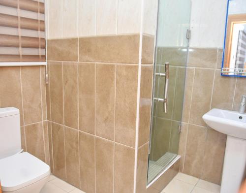 a bathroom with a shower and a toilet and a sink at Orchids Service apartments in Lagos