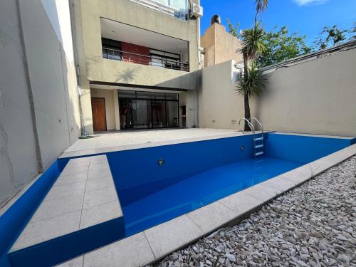 uma piscina azul em frente a uma casa em Semipiso premium con piscina y cochera opcional em La Plata