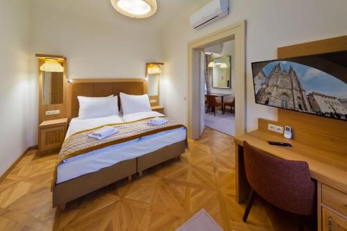 une chambre avec un lit, un bureau et une télévision dans l'établissement Havelska Old Town Residence, à Prague