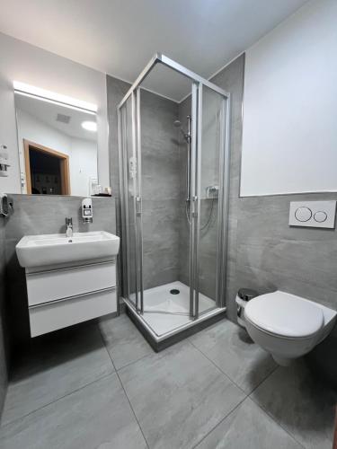 a bathroom with a shower and a toilet and a sink at Hotel Wilhelmshöhe in Warnemünde