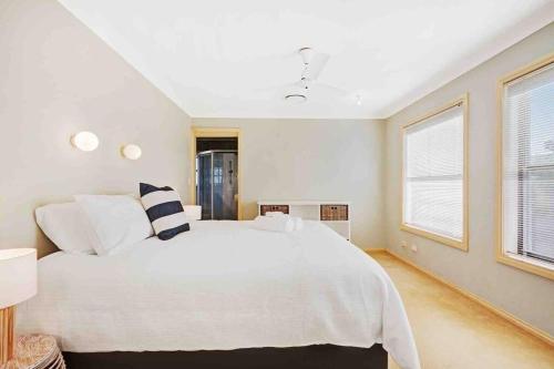 a white bedroom with a large white bed and two windows at Booker Bay Ocean View in Booker Bay