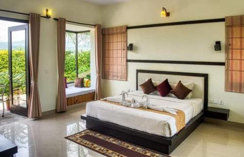 a bedroom with a large bed and a balcony at Corbett Wild Nature View Resort in Rāmnagar