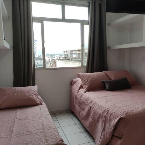 a bedroom with two beds and a large window at Kitnet no centro de Guarapari in Guarapari