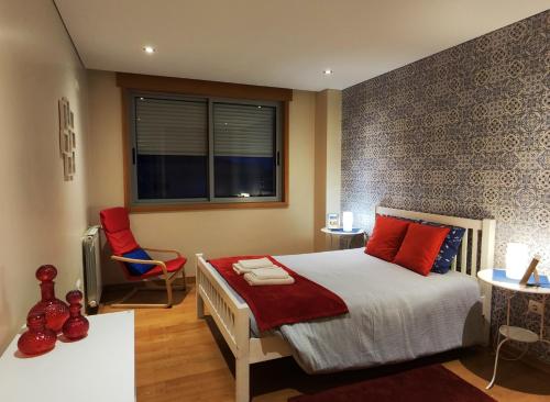 a bedroom with a bed with red pillows and a window at Portus Cale Apartment in Águas Santas