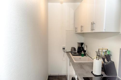 une cuisine avec des armoires blanches et un évier dans l'établissement Le Nid Cosy -Au Cœur d'Orléans, à Orléans