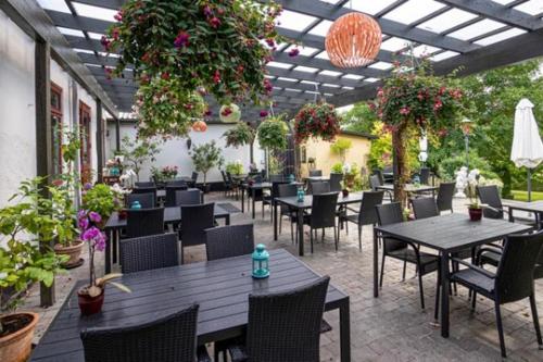 un restaurante con mesas, sillas y plantas en Lynge kro & Hotel 