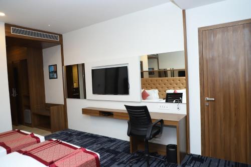 a room with a desk with a tv and chairs at Regenta Inn Morbi in Morbi