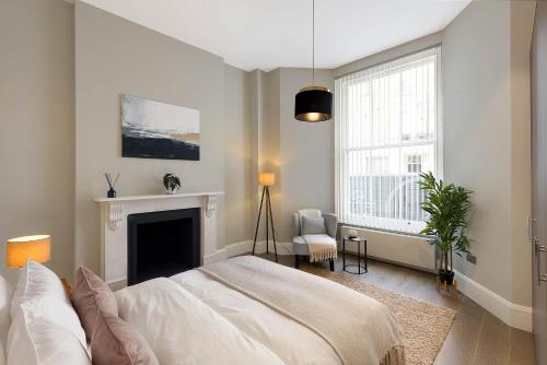 een witte slaapkamer met een bed en een open haard bij Beautiful Serviced Apartment London in Londen