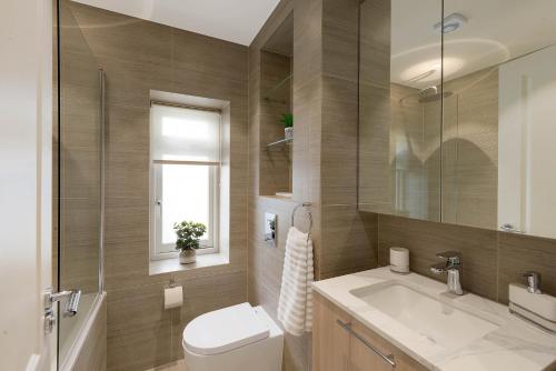 een badkamer met een toilet, een wastafel en een spiegel bij Beautiful Serviced Apartment London in Londen