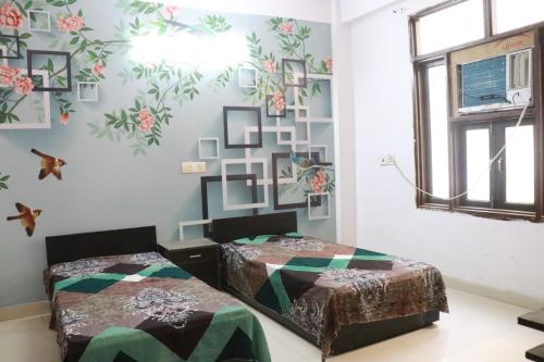 2 camas en una habitación con flores en la pared en Tanmay Homes and PG, en Gurgaon