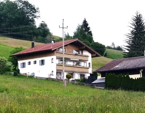 une maison blanche avec un toit rouge sur une colline dans l'établissement Jungholz Erlebnis, à Jungholz