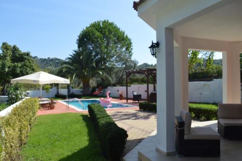 einen Hinterhof mit einem Pool und einem Haus in der Unterkunft Villa Platanias in Agia Paraskevi