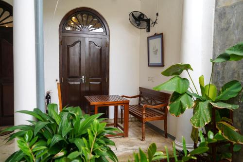 a room with a wooden door and a table and plants at Fort Bliss in Galle