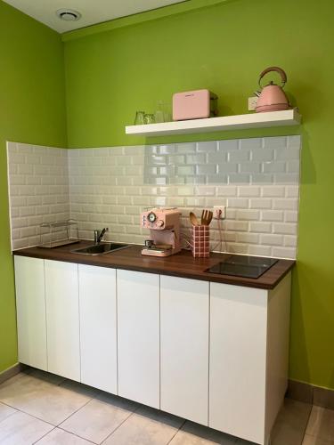 a kitchen with white cabinets and green walls at Appartement Ibiz’Arles in Arles