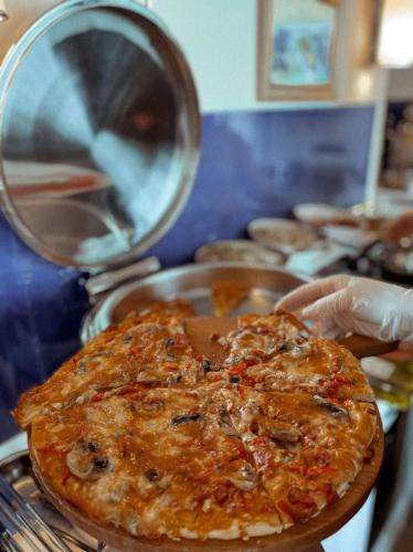 a person is holding a pizza on a pan at INTERSTELLAR ☆ ORBI CITY in Batumi