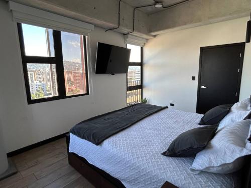 a bedroom with a bed and two windows at EÓN 13 - Apto moderno con aire acondicionado in Guatemala